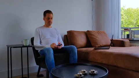 Man is working from home and is typing on his phone Stock Footage 211900711