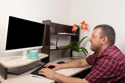 Man working at home at the computer takes notes Stock Photos