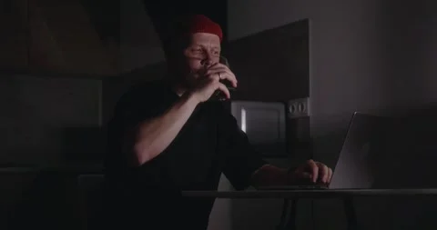 A man is working at home in the dark using a laptop in the kitchen Stock Footage 302900488