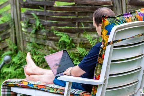 Man working from home in the garden using smart phone and notebook computer Foto stock