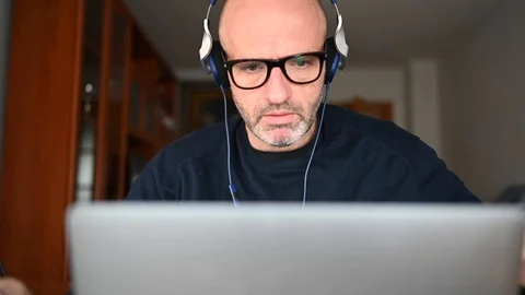 Man working from home on a laptop computer sitting at a desk surfing the inte Stock-Footage 127711725
