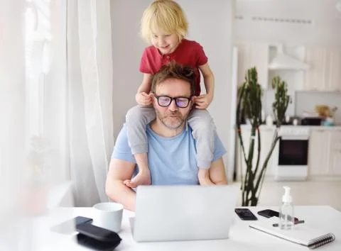 Man working from home with laptop during quarantine. Home office and parentho Stock Photos
