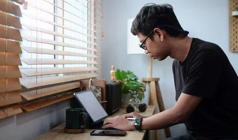 Man working from home on laptop while sitting at the living room, drinking co Stock Photos