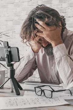 Man working at home on the table with desperate expression and posture. Mal.. 스톡 사진