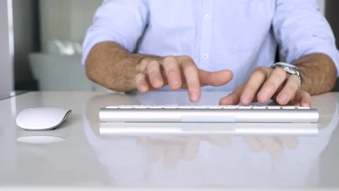 Man working at home, typing on smart keyboard at modern white table Stock Footage 233147140