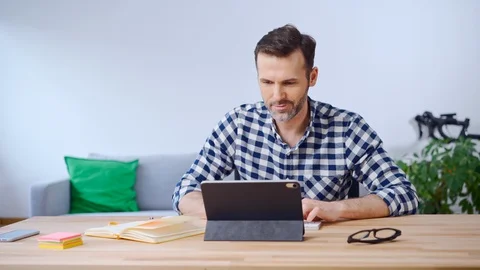 Man working from home using digital tablet and doing notes in notebook Stock Footage 126857331