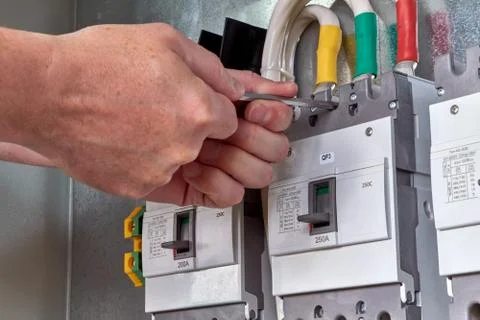 Man working key screws the circuit breaker to the circuit Board. Stock Photos