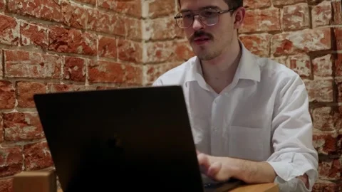 Man working on laptop against brick wall 库存影片 342779759