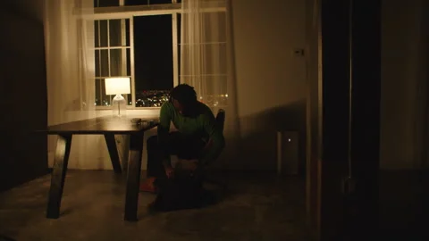 Man working on laptop alone at night in a dimly lit room Stock Footage 312584054