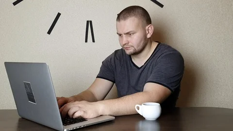 A man working on a laptop and drinking coffee Stock Footage 121337338