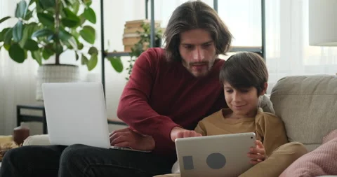 Man working on laptop and son using digital tablet Stock Footage 145227979