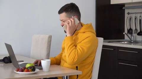 Man working on laptop and talking on a phone Stock Footage 127527595