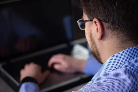 Man working on laptop back view in home environment Stock Photos