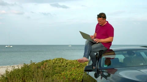 Man working with a laptop by the beach Stock Footage 132903370