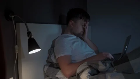 Man working on laptop in bed at night. Guy with insomnia was lying on bed using Stock Footage 145494766
