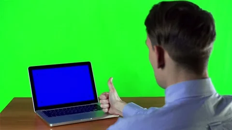 Man working at a laptop with blue screen with showing thumbs up Stockbeeldmateriaal 49685001