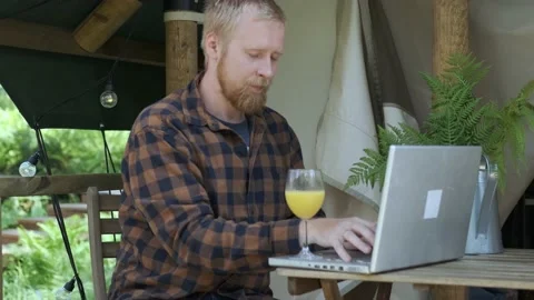 A man working on a laptop in a camping and drinking juice Video stock 154280254