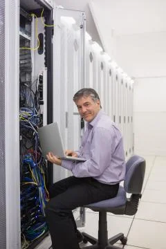 Man working on laptop to check servers Stock Photos