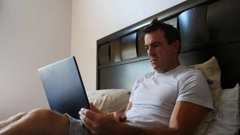 Man working on laptop computer in bed in the morning after waking up, 4k, 60fps. Stock Footage 116335917
