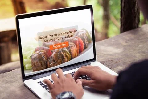 Man working on laptop / computer, doing subscribe food blog on screen at the par Stock Photos