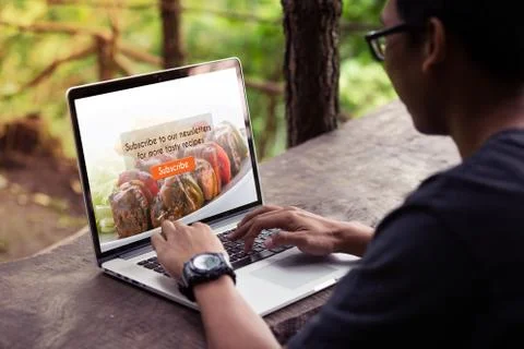 Man working on laptop / computer, doing subscribe food blog on screen  Stock Photos