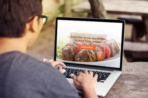 Man working on laptop / computer doing subscribe food blog on screen at the park Stock Photos