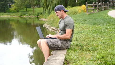 Man working on laptop computer outdoors thinking, 4k, 60fps. Stock Footage 115900934