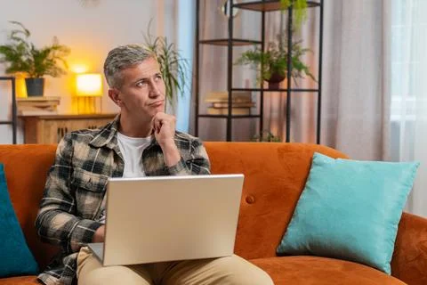 Man working on laptop computer with pensive expression, pondering a solution Stock Photos