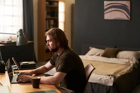 Man Working on Laptop Computer While Telecommuting at Home Stock Photos