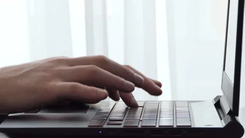 A man working with a laptop on a desktop next to a window. Male freelance Stock Footage 178089928
