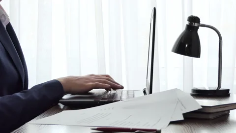 A man working with a laptop on a desktop next to a window. Male freelance Stock Footage 178099518