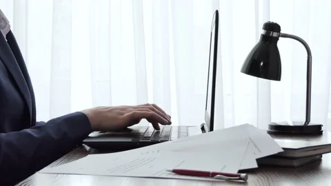 A man working with a laptop on a desktop next to a window. Male freelance Stock Footage 178619634