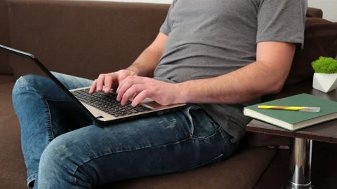 Man working on laptop device leaning on sofa at home. Man working distantly typi Stock Footage 168532108