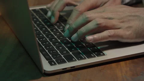 A man working on a laptop in a dimly lit room Stock Footage 333958255