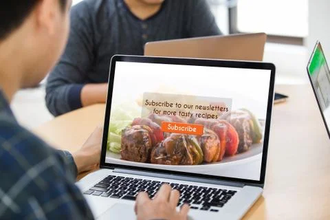 Man working on laptop doing subscribe food blog on screen at office Stock Photos