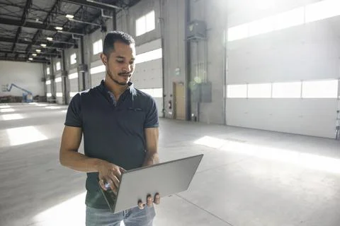 Man working on laptop in empty warehouse Stock Photos