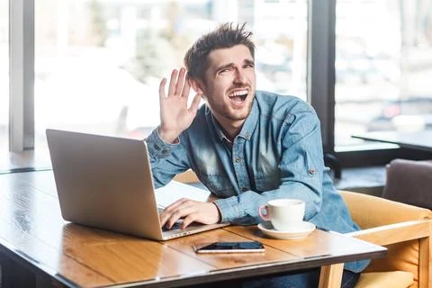 Man working on laptop, having problems with microphone speaker, keeps hand near 스톡 사진