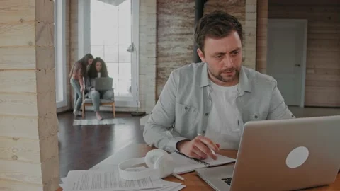 Man working at the laptop at home because of covid-19, family in the background Stockbeeldmateriaal 165411547