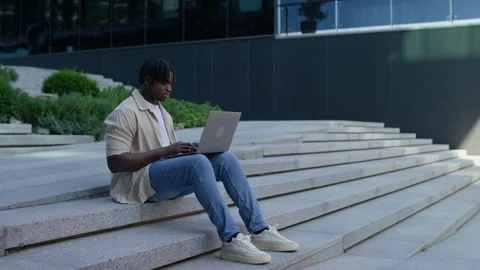 Man working on laptop outdoors on steps Stock Footage 314369610