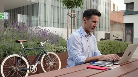 Man working on laptop outside the workplace with bicycle Stock Footage 306659084