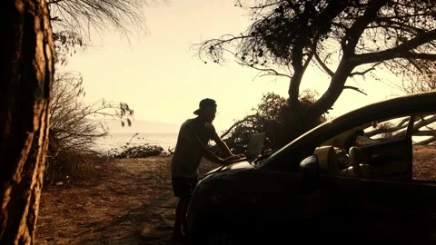 Man Working on Laptop Placed on Car Hood by the Sea at Sunset 動画素材 341939642