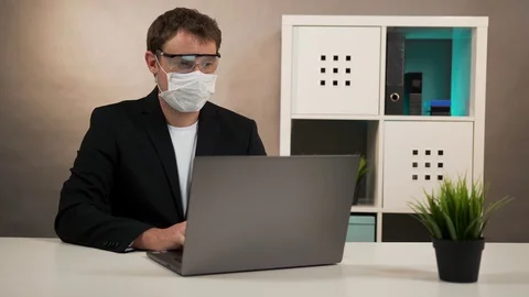 Man working on laptop in protective glasses and mask Stock Footage 128998293