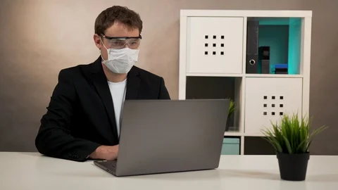 Man working on laptop in protective glasses and mask Stock Footage 128998300