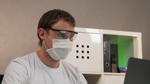 Man working on laptop in protective glasses and mask Stock Footage 129049296