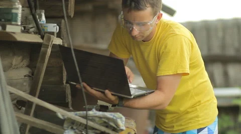 A man working on a laptop, puts aside the computer and begins sawing metal with Stock Footage 64999322