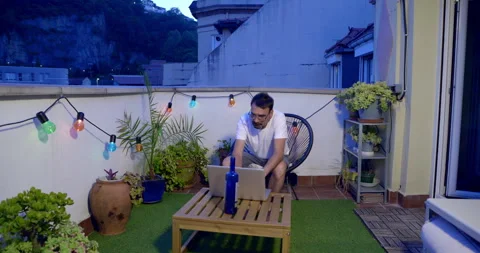 Man Working on Laptop on Rooftop Terrace at Dusk Stock Footage 336240513