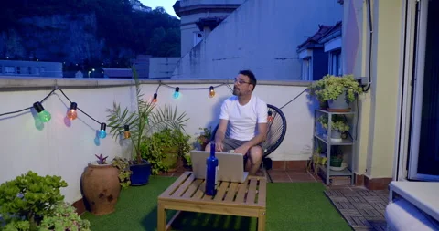 Man Working on Laptop on Rooftop Terrace at Dusk Stock-Footage 336244824