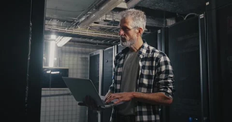 Man Working on Laptop in Server Room Видео 277940950