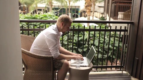 Man working on a laptop sitting on the terrace of the hotel 動画素材 85933664