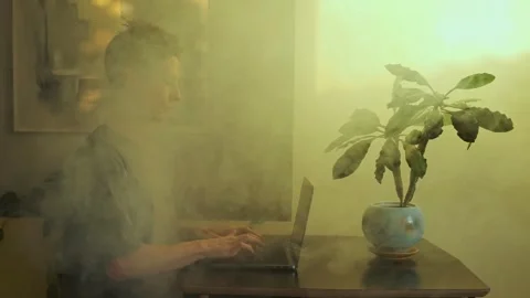Man Working on Laptop Surrounded by Smoke, Symbolizing Work Burnout in Stock Footage 307786905